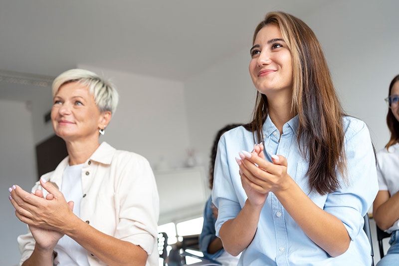 Frauen lauschen Vortrag und klatschen